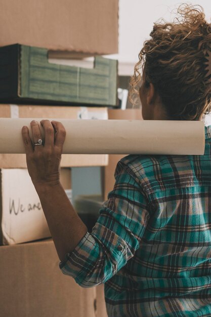 Photo vue arrière d'une femme devant de nombreuses boîtes en carton après un prêt hypothécaire de déménagement nouvelle maison et vie les femmes indépendantes profitent des loisirs d'un appartement plat concept de réinstallation et de location maison intérieure