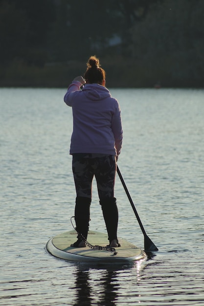 Photo vue arrière d'une femme faisant du paddleboard dans un lac