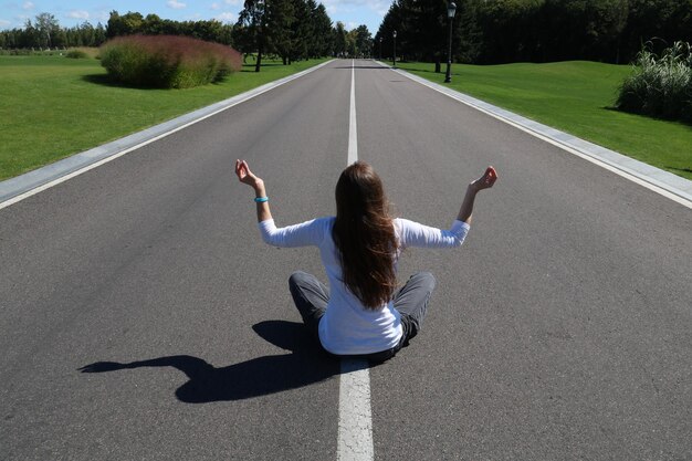 Photo vue arrière d'une femme faisant du yoga sur la route