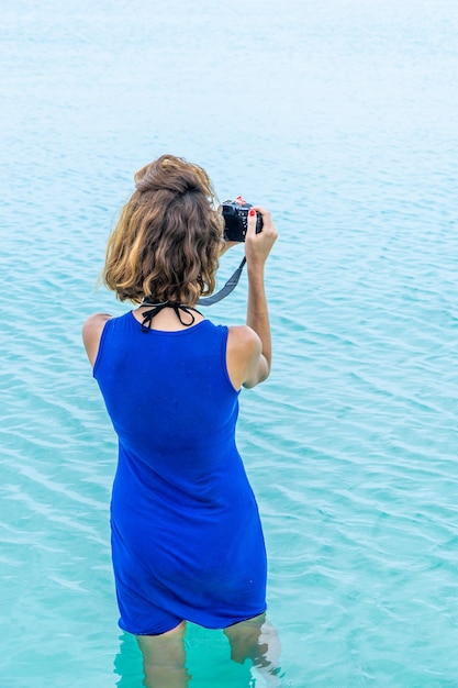 Vue arrière d'une femme Femme méconnaissable debout sur l'eau bleue et prenant des photos. Vue arrière.