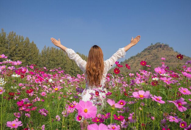 Photo vue arrière d'une femme avec des fleurs roses sur le champ contre le ciel