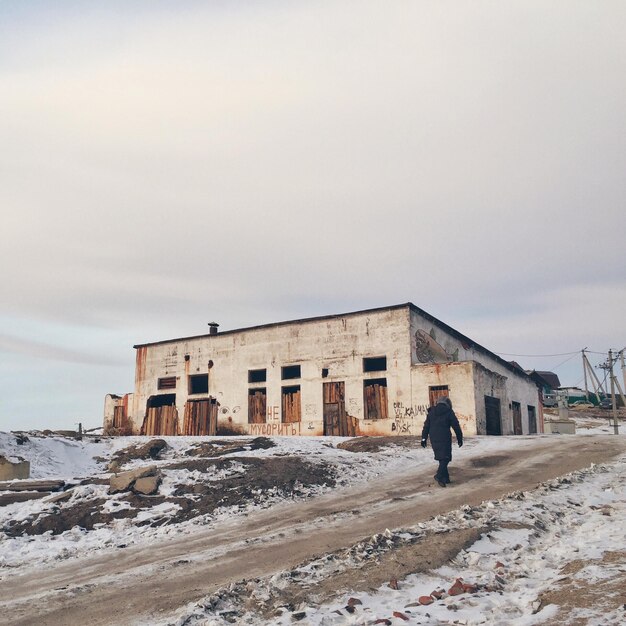 Photo vue arrière d'une femme marchant devant un bâtiment contre le ciel en hiver