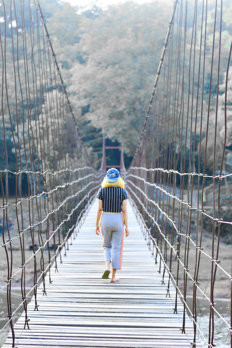 Photo vue arrière d'une femme marchant sur une passerelle dans la forêt