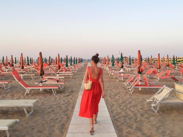 Photo vue arrière d'une femme marchant sur la plage contre un ciel clair