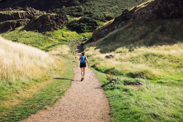 Vue arrière d'une femme marchant sur une route de terre