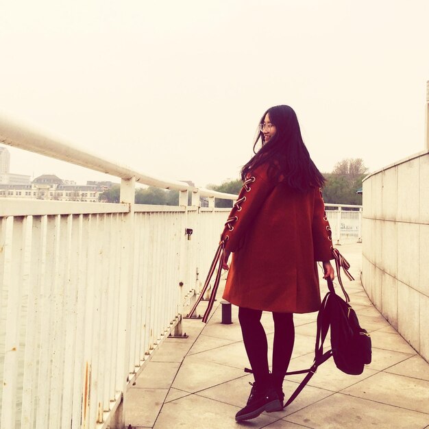 Photo vue arrière d'une femme marchant avec un sac par la balustrade sur le trottoir