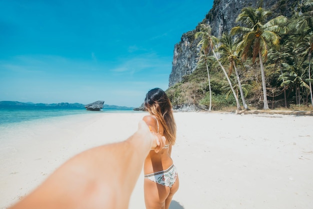 Vue arrière d'une femme marchant en se tenant par la main sur la plage
