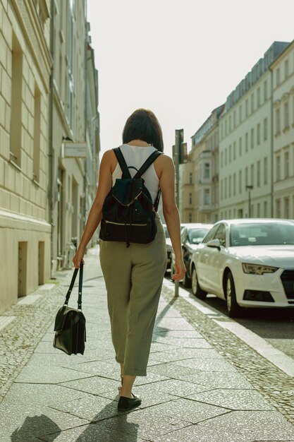 Vue arrière d'une femme marchant sur le trottoir en ville pendant une journée ensoleillée