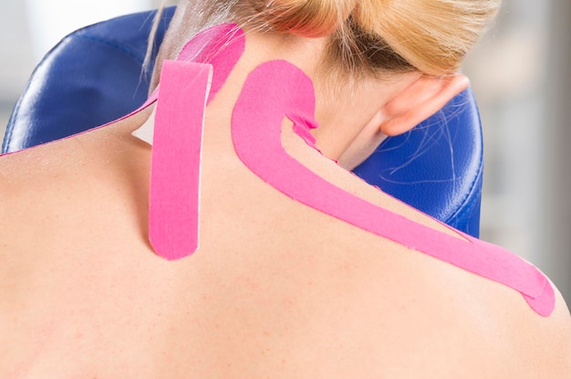 Vue arrière d'une femme mature avec un ruban kinesio rose sur le dos