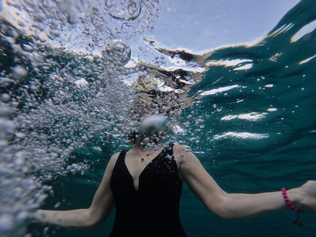 Photo vue arrière d'une femme nageant dans la mer