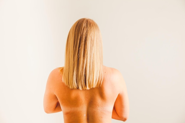 Vue arrière femme nue aux cheveux blonds raides Traces de soutien-gorge sur le dos de la femme Studio tourné sur fond blanc non filtré