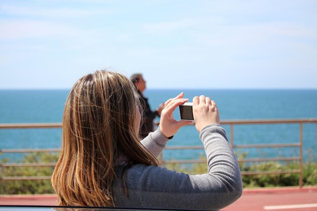 Photo vue arrière d'une femme photographiant avec un appareil photo numérique