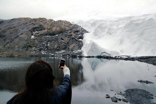 Photo vue arrière d'une femme photographiant dans le lac contre le ciel