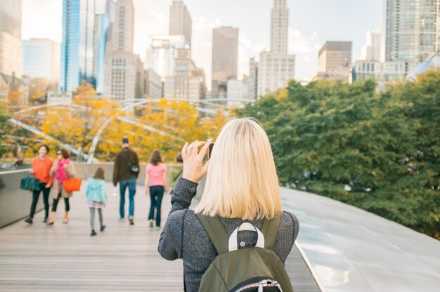 Vue arrière d'une femme photographiant à travers un smartphone depuis le pont BP