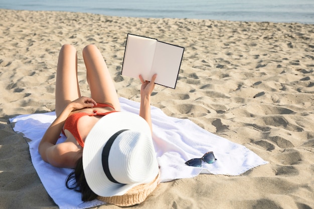 Vue arrière, femme, plage, lecture livre