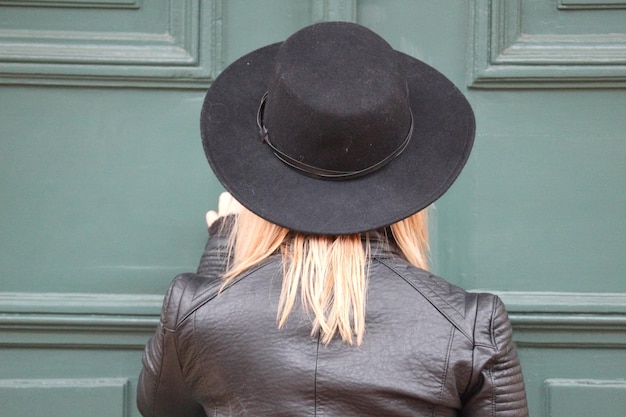 Photo vue arrière d'une femme portant un chapeau contre une porte fermée