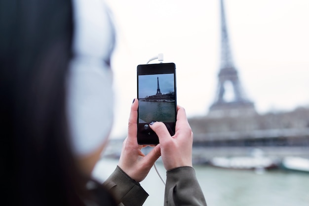 Vue arrière d'une femme prenant une photo de la tour Eiffel depuis la Seine à Paris, France.