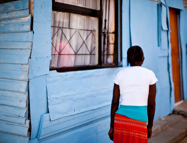 Photo vue arrière d'une femme qui passe devant une maison dans un village