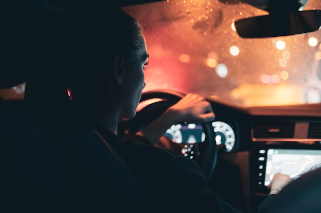 Vue arrière d'une femme regardant une carte en conduisant une voiture