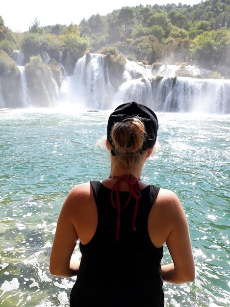 Vue arrière d'une femme regardant une cascade