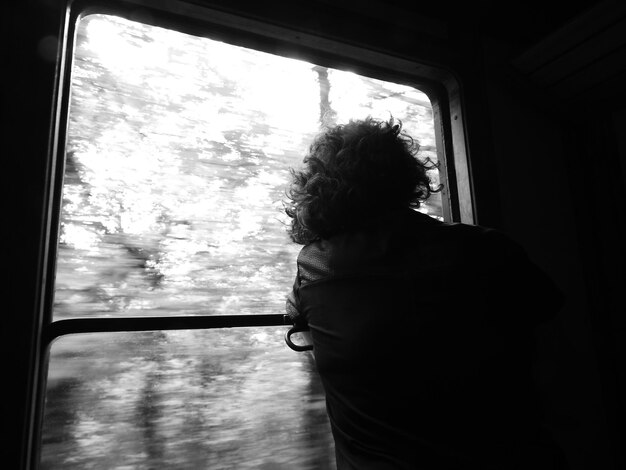 Vue arrière d'une femme regardant par la fenêtre d'un train