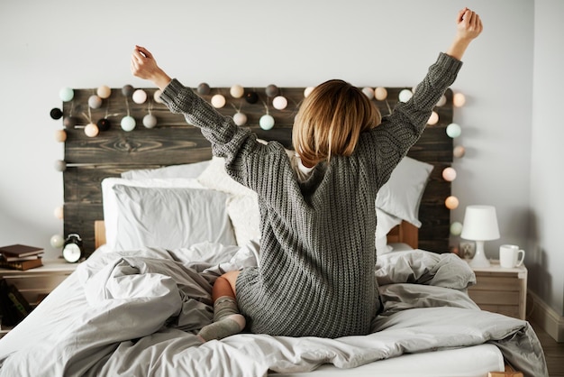 Photo vue arrière d'une femme s'étirant sur le lit à la maison