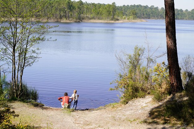 Vue arrière de la femme avec sa fille regardant de côté le lac au bord du lac