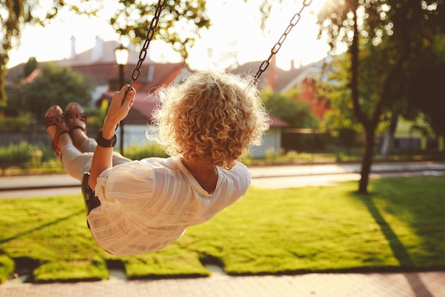 Photo vue arrière d'une femme se balançant dans un parc