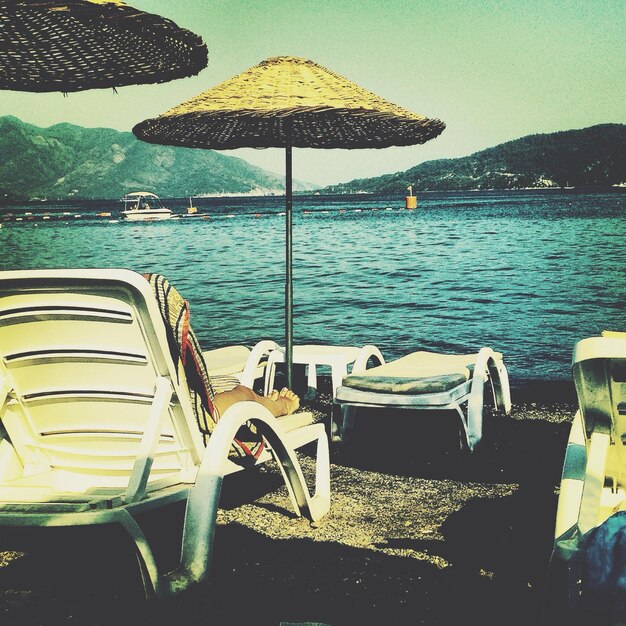 Photo vue arrière d'une femme se détendant sur une chaise longue par la mer sur la plage