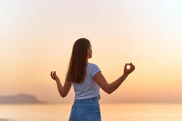 Vue arrière d'une femme sereine et heureuse, satisfaite et calme, debout seule sur la plage au bord de la mer Soins de santé mentale et moment de soulagement