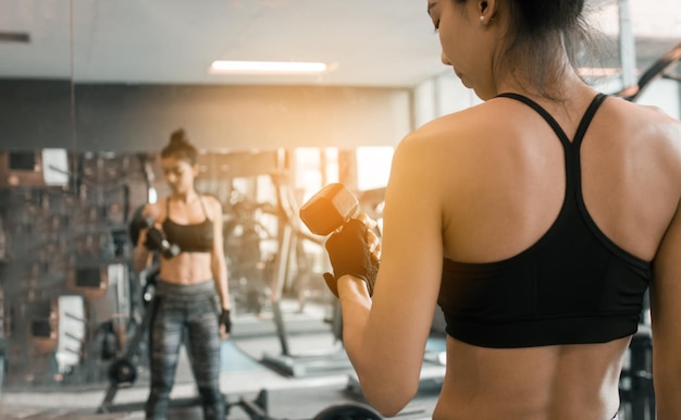 Vue arrière d'une femme soulevant un haltère dans la salle de sport