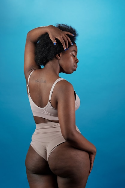 Photo vue arrière d'une femme de taille plus en sous-vêtements touchant ses cheveux