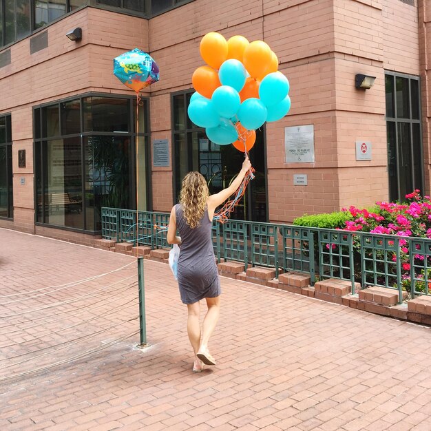 Photo vue arrière d'une femme tenant des ballons colorés