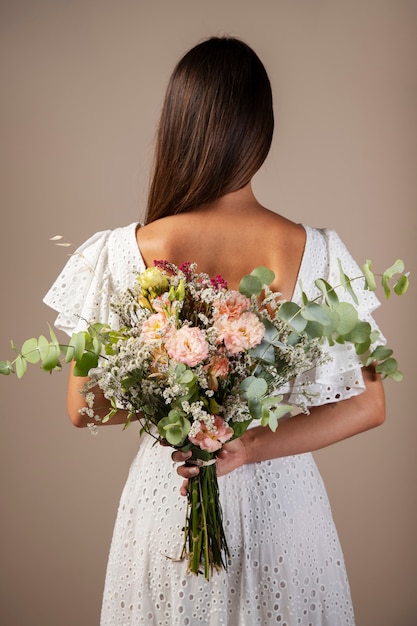 Photo vue arrière femme tenant un bouquet de fleurs