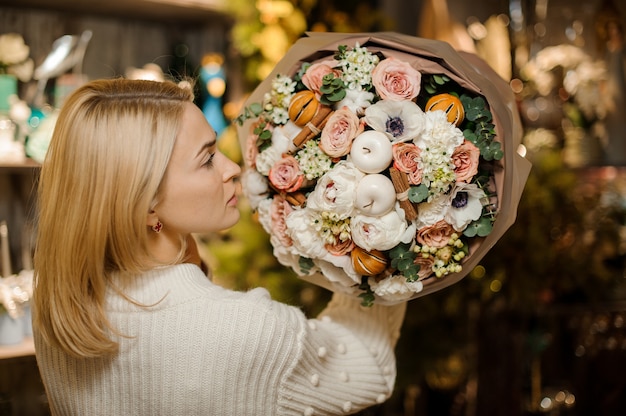 Vue arrière femme tenant un bouquet de roses de couleur blanche et pêche avec des pommes