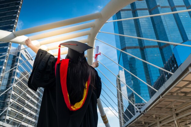 Photo vue arrière d'une femme tenant un certificat alors qu'elle se tient contre une structure métallique construite