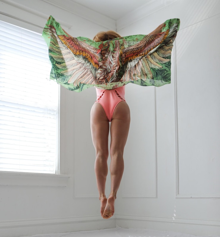 Photo vue arrière d'une femme tenant un foulard en lévitation à la maison
