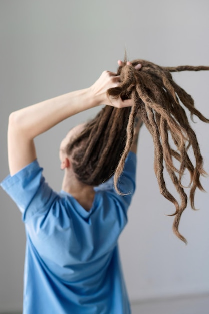 Photo vue arrière d'une femme tenant de longs dreadlocks devant la caméra minimale