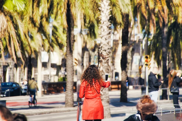 Photo vue arrière d'une femme utilisant un téléphone portable dans la rue de la ville