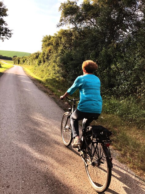 Photo vue arrière d'une femme à vélo sur la route