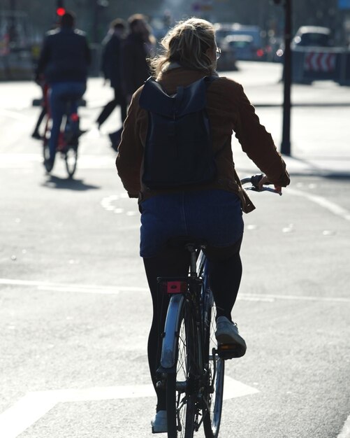 Photo vue arrière d'une femme à vélo sur la route