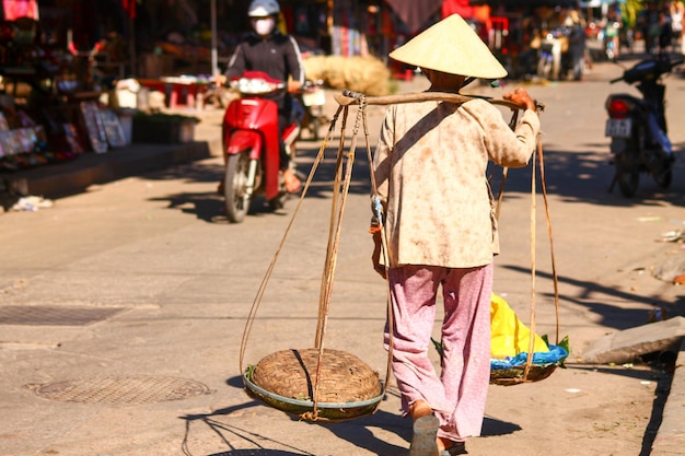 Vue arrière d'une femme vietnamienne vendant de la nourriture de rue sur un poteau d'épaule