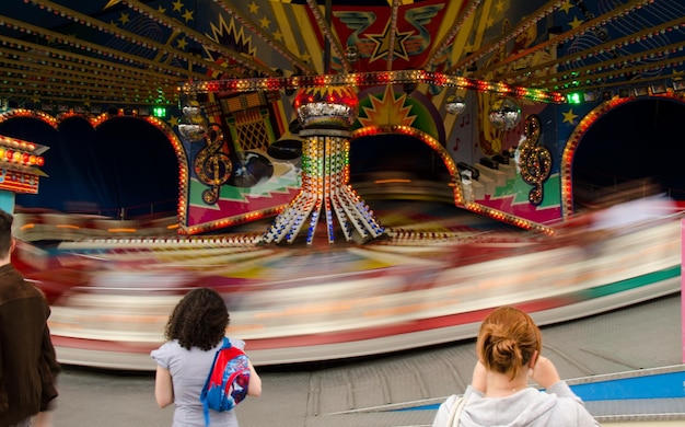 Vue arrière des femmes regardant le carrousel flou