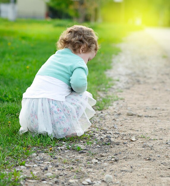 Vue arrière d'une fille accroupie sur l'herbe