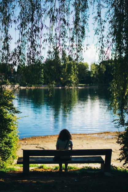 Vue arrière d'une fille assise sur un banc dans un parc