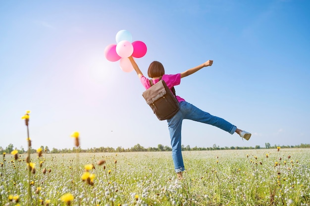 Vue arrière d'une fille avec des ballons sur terre