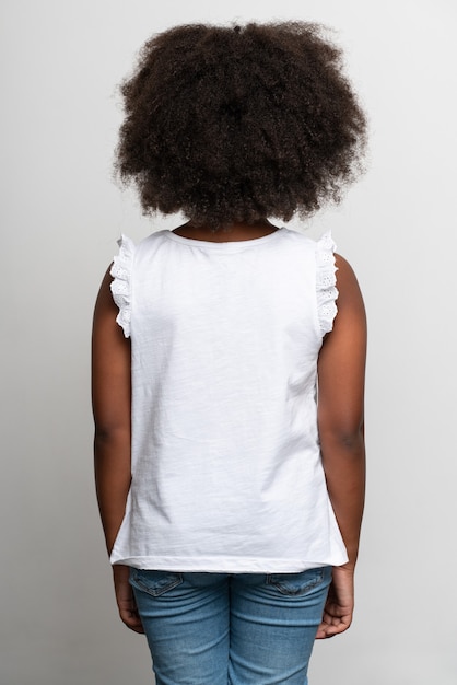 Vue arrière de la fille multiraciale portant un T-shirt blanc. Notion d'enfance. Isolé sur fond blanc, tourné en studio