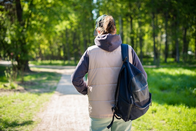 Vue arrière d'une fille solitaire ou d'une jeune femme voyageant dans une casquette de baseball et avec un sac à dos