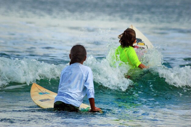 Photo vue arrière de filles faisant du surf en mer