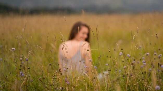 Vue arrière floue femme assise sur l'herbe